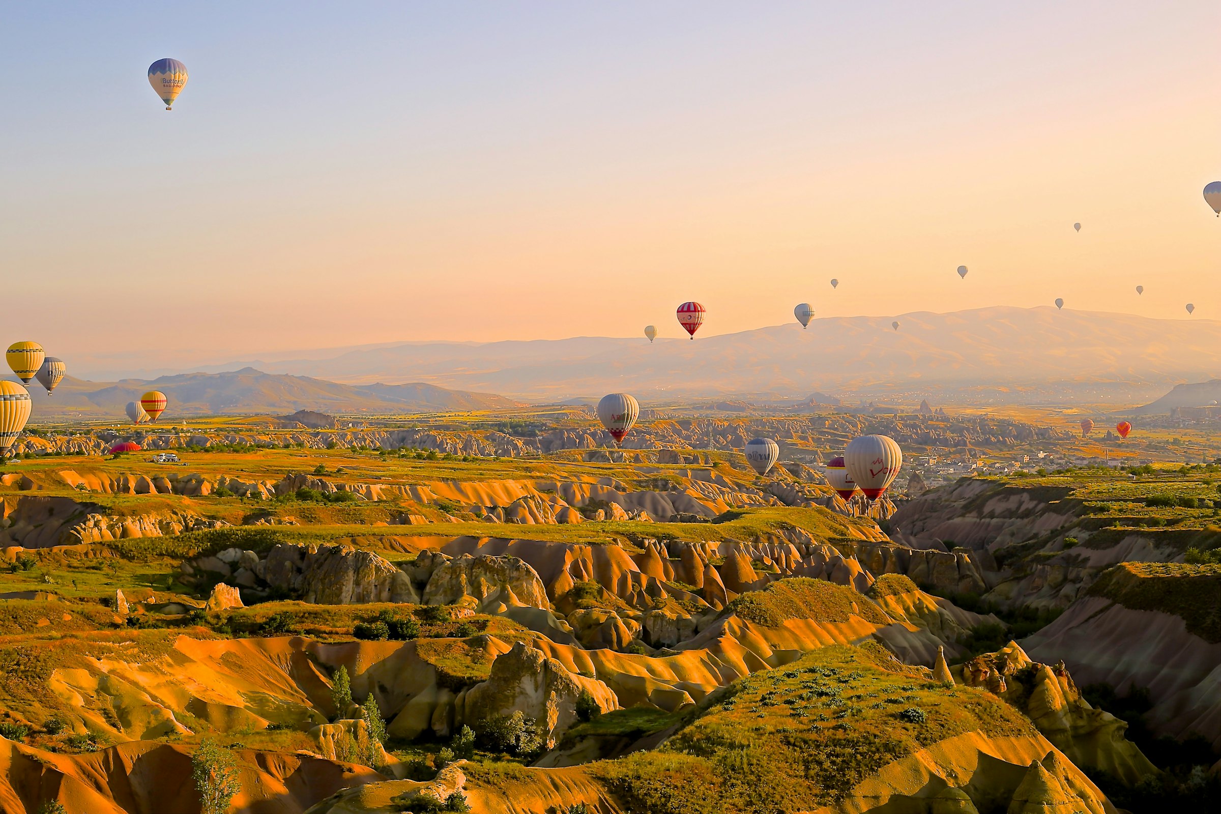 Hot air balloons drifting over a valley of rock formations at sunrise