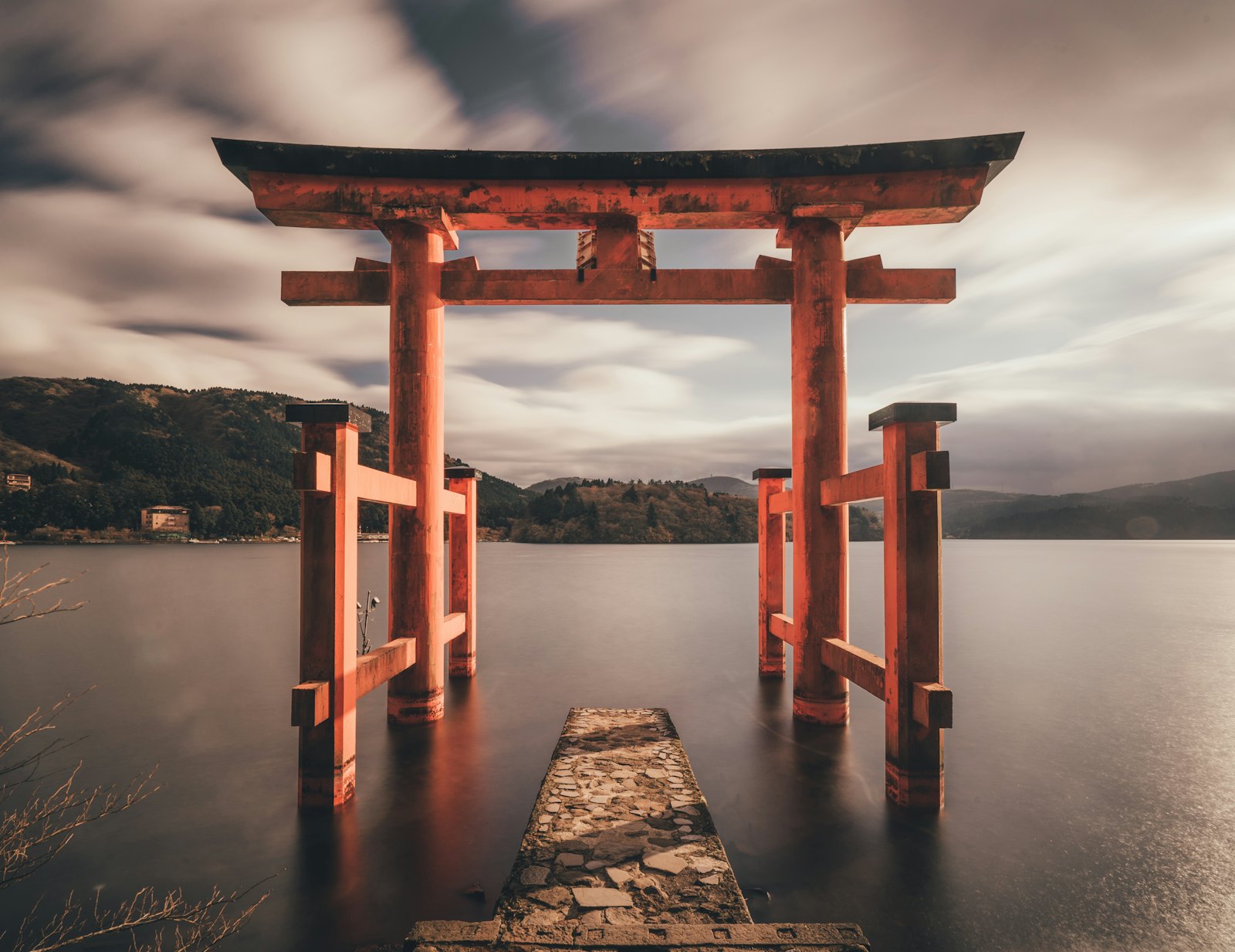 A red torii gate standing in still water under a grey sky