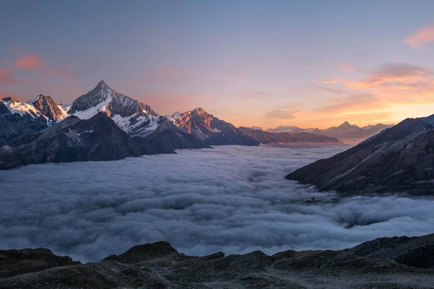 Mountain peaks rising out of a sea of cloud at sunset